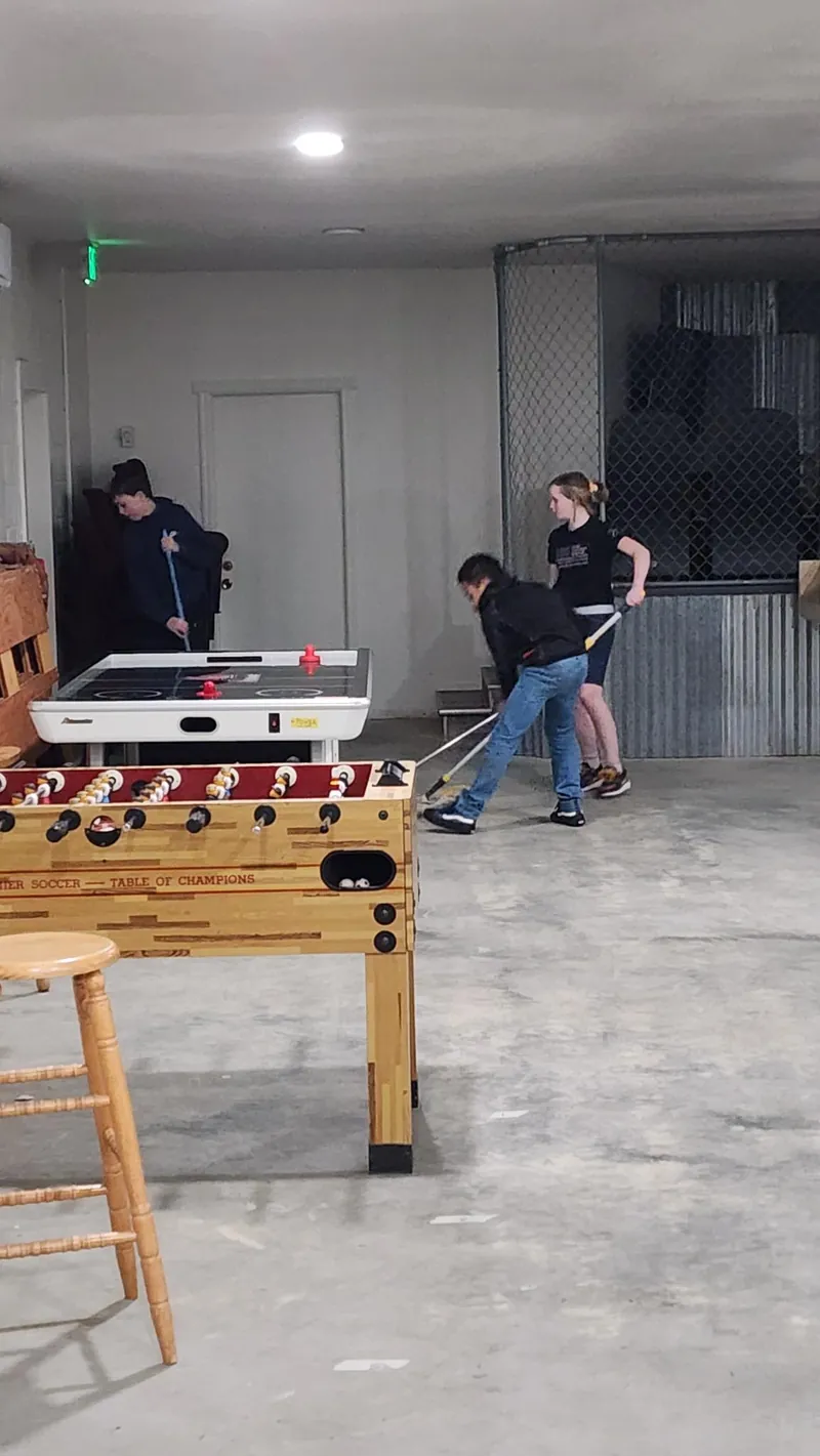 Students playing air hockey and floor games in The Refuge game room